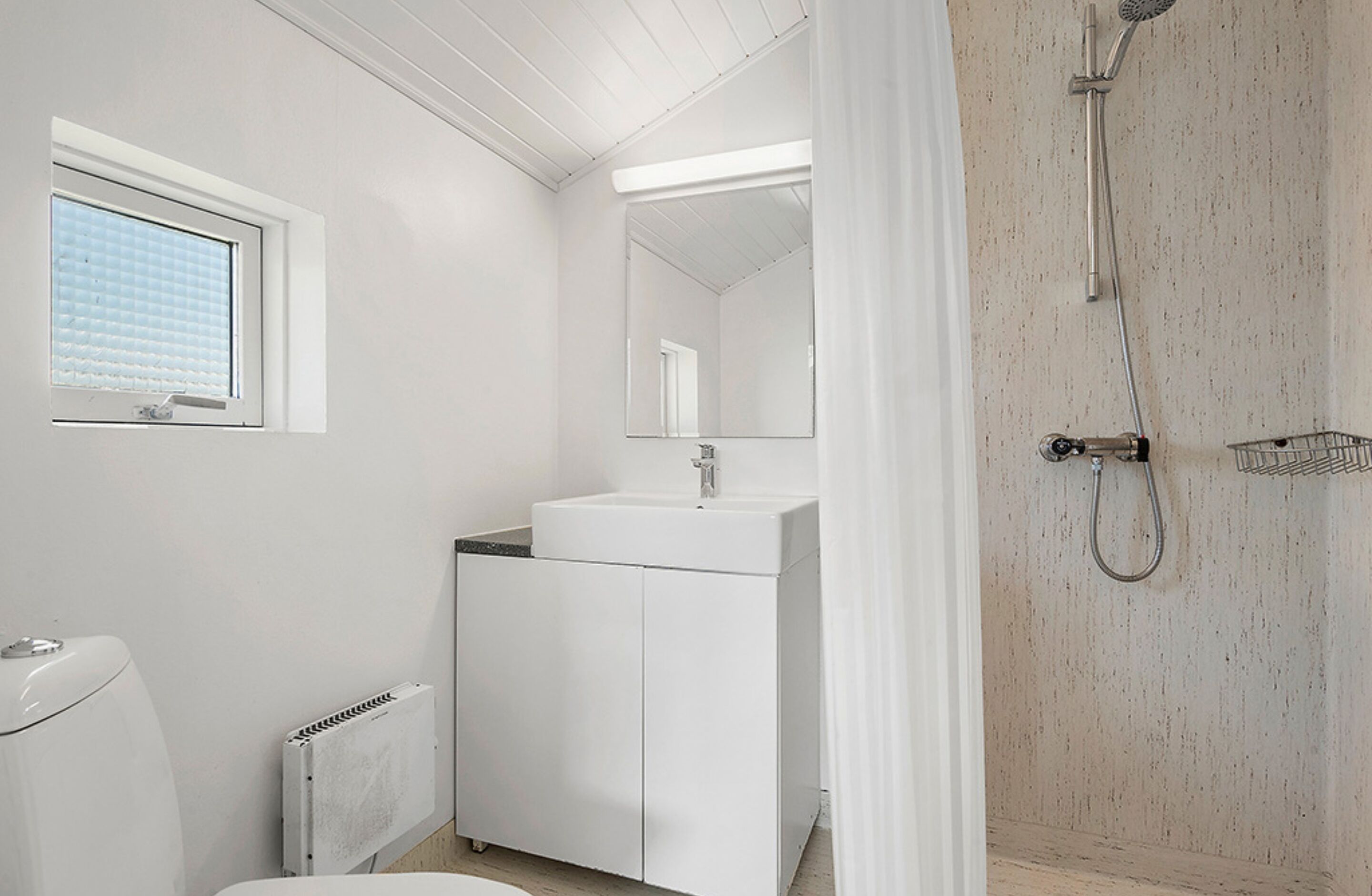 A bathroom with a white sink, mirror, and shower.