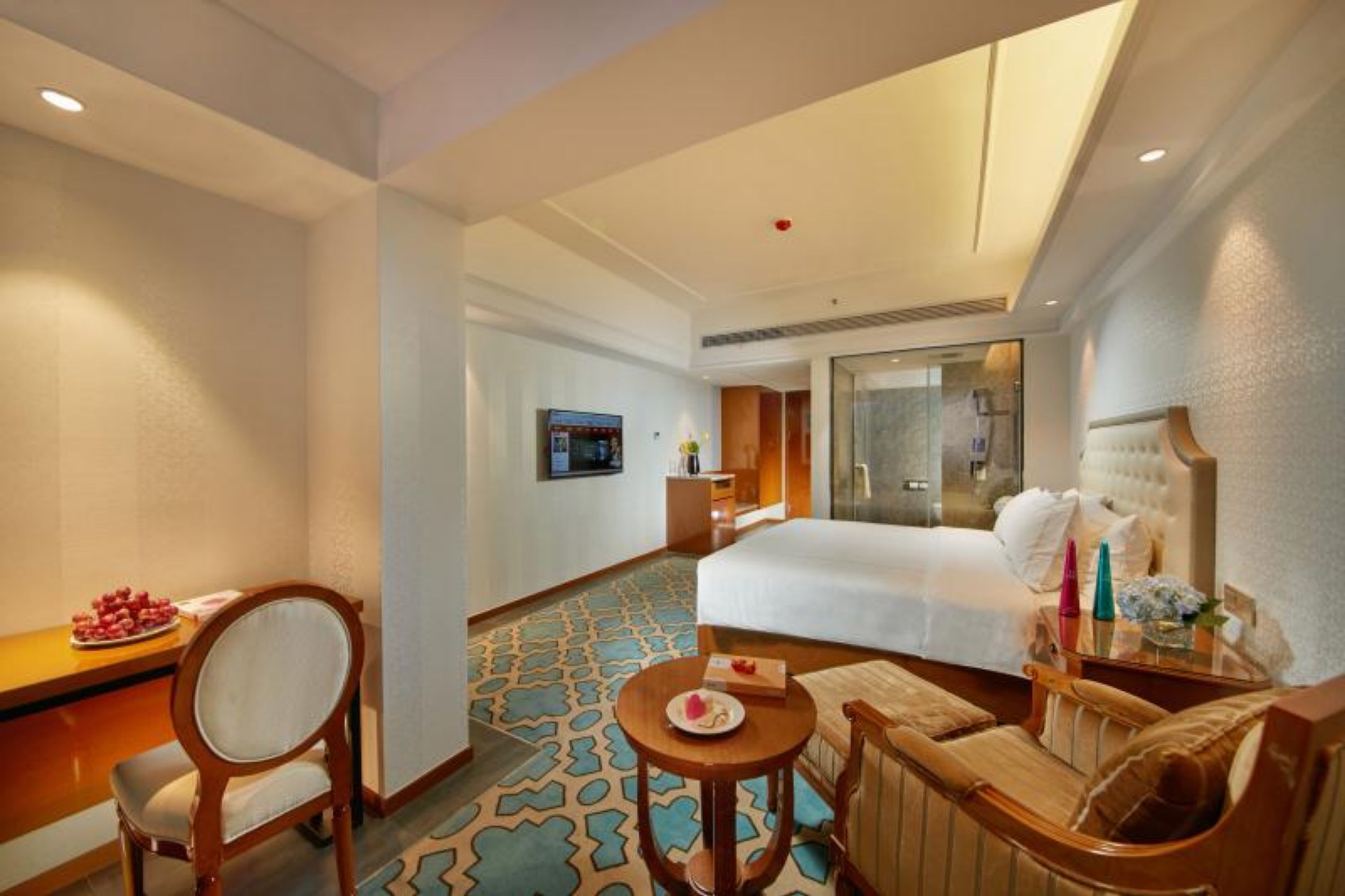 Habitación de hotel con una cama grande, un escritorio con silla, una mesita con un plato y un sofá.