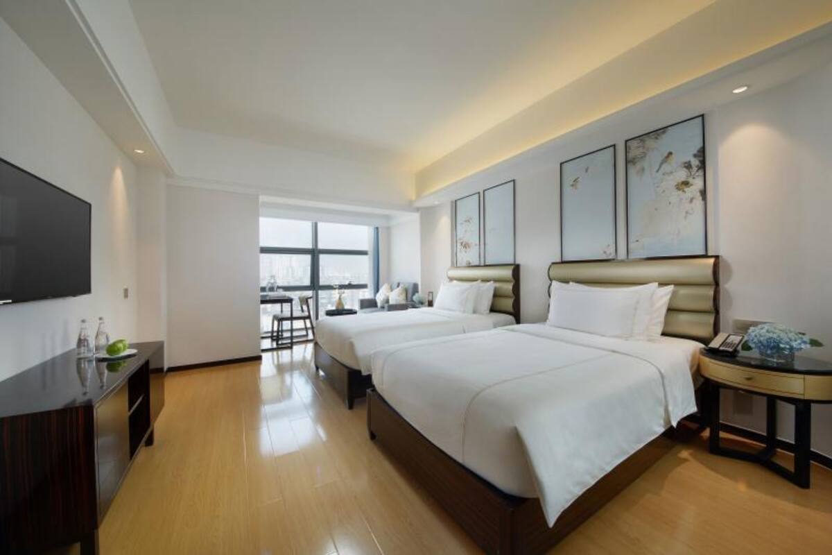 Habitación de hotel con dos camas, televisión, escritorio y ventana con vistas.
