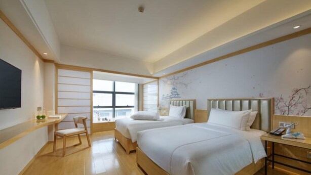 Een hotelkamer met twee bedden, een bureau, een stoel en een televisie.