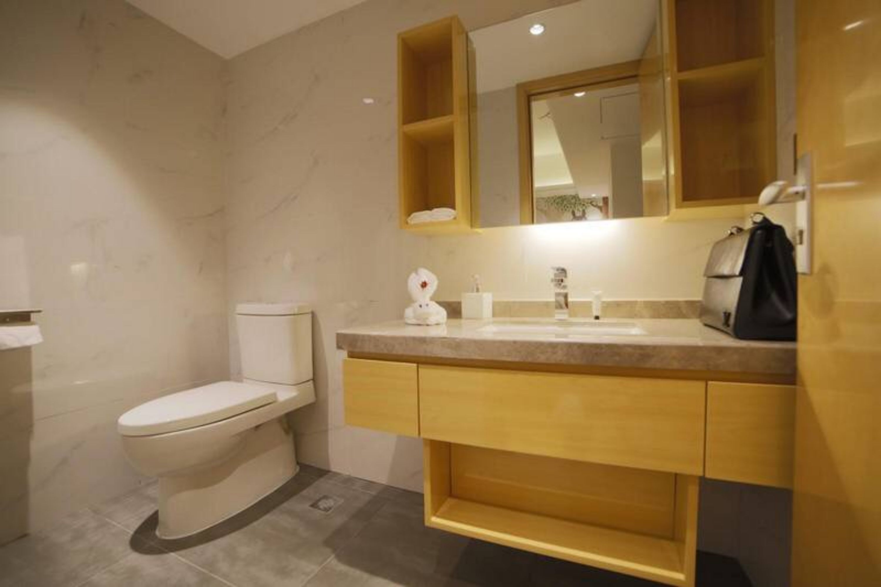 Egy modern fürőszoba, amelyben található egy WC, egy mosdókagyló és egy tükör a mosdó fölött.
