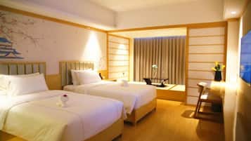 A hotel room with two beds, a desk, and a chair.