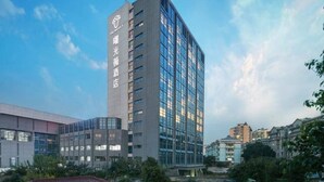 Een modern hotelgebouw met een opvallend logo op de gevel, meerdere verdiepingen en een glazen buitenkant.