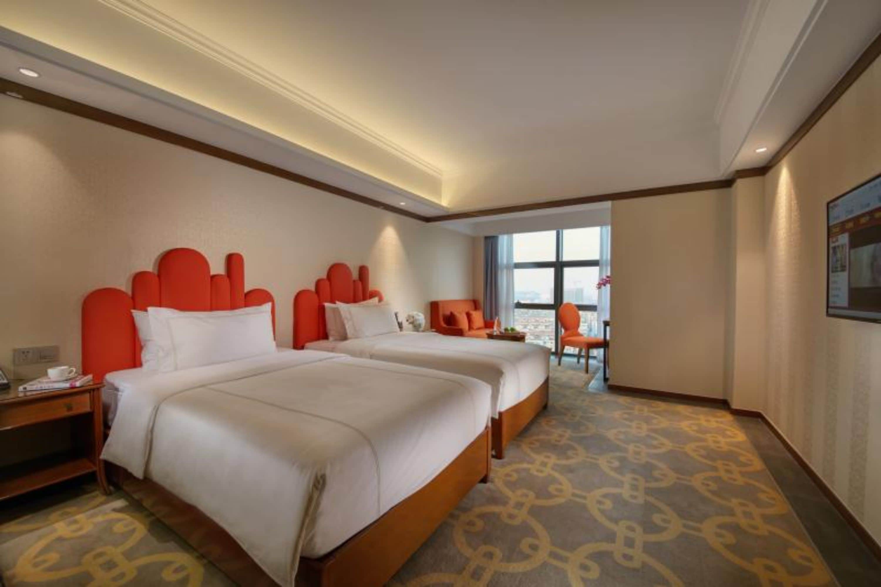 A hotel room with two beds, a desk, and a chair.