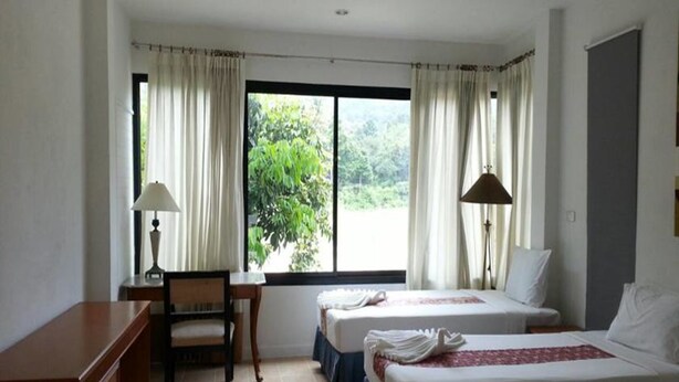 A hotel room with two beds, a desk, a chair, and a window with curtains. - The Tree Madauwan (Ko Pha-ngan)