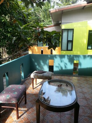 A patio area with a glass table, a cushioned bench, and a patterned chair.