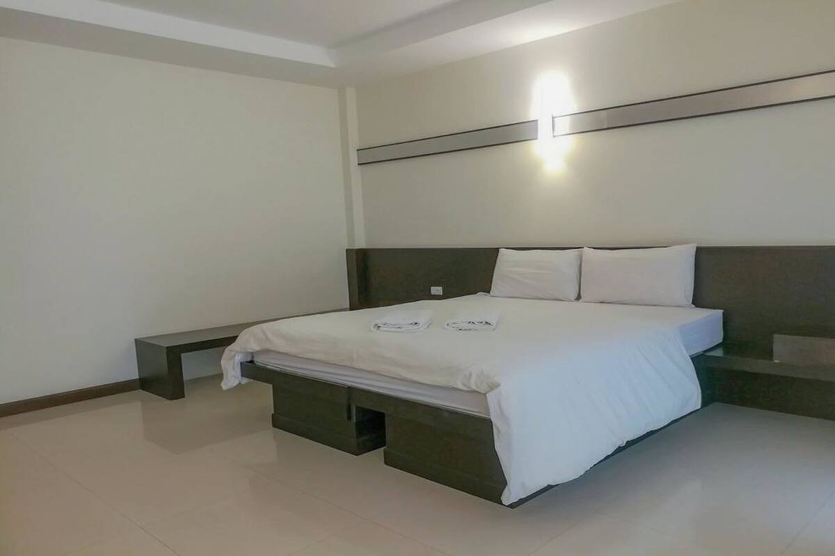 A modern bedroom with a bed, bedside tables, and a bench.