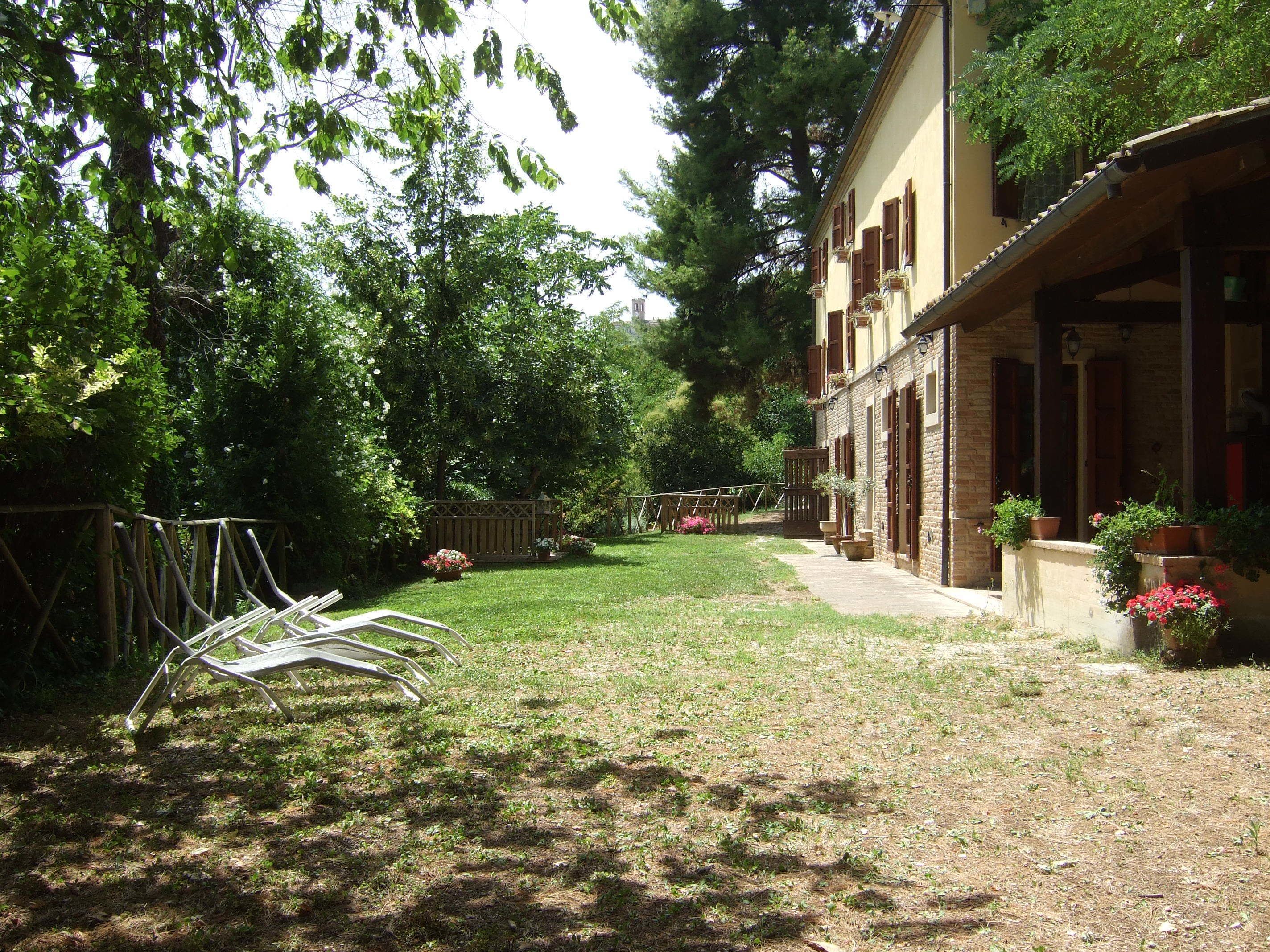 A courtyard with a grassy area, a wooden fence, and a building with a brick facade and wooden shutters.
