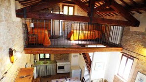 Un coin repas rustique avec une table dressée pour deux personnes, un buffet en bois et une chaise.