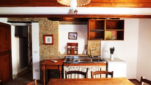 Une cuisine avec une table en bois, des chaises, une cuisinière et un évier.