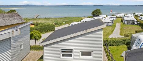 A campsite with RVs and mobile homes, a grassy area, and a body of water in the background.