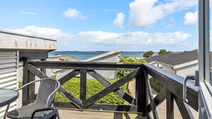A balcony with a view of the sea, a chair, and a table.