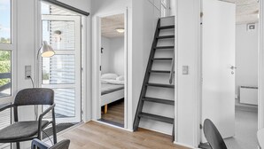 A modern interior with a bed, a chair, a desk, and a staircase.