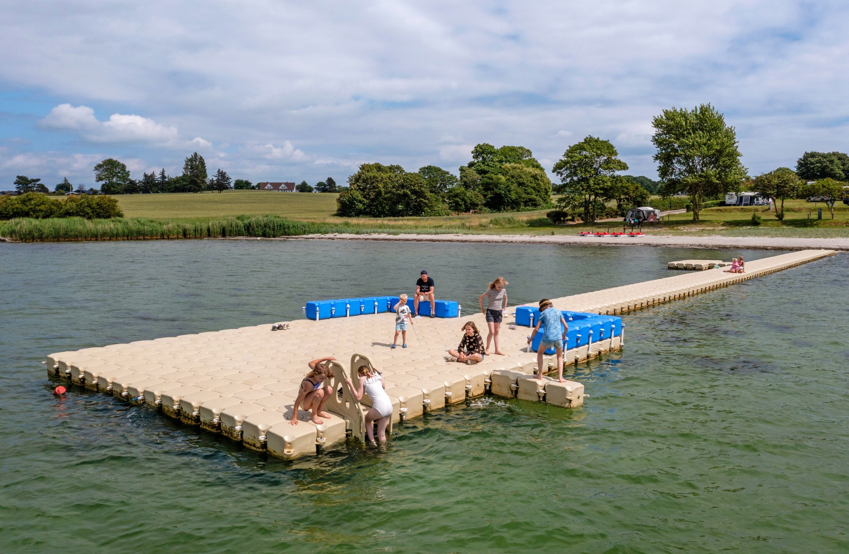 Een steiger die zich uitstrekt in een kalm wateroppervlak, met mensen die er verschillende activiteiten ondernemen.