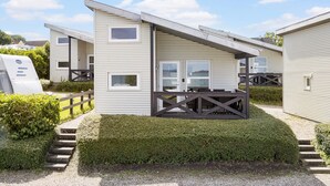 A row of mobile homes with a small deck and steps leading to the entrance.
