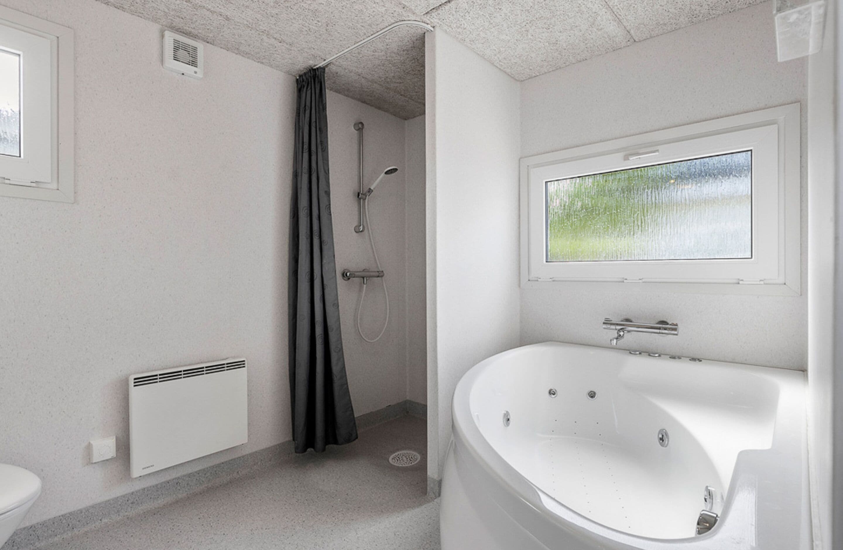 A modern bathroom with a shower, a bathtub, a window with a view, and a radiator.