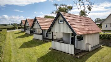 A row of small, single-story cabins with pitched roofs, arranged in a row on a grassy field.