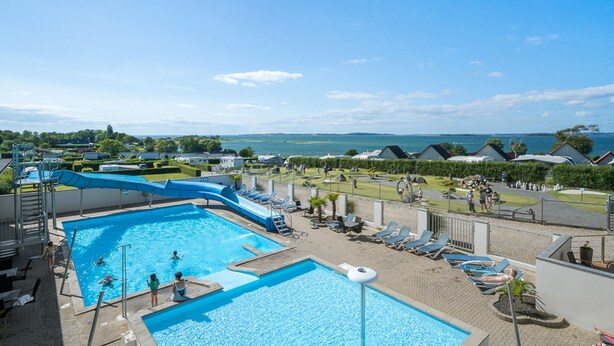 A pool area with multiple swimming pools, lounge chairs, and a water slide.
