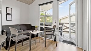 A modern living room with a sofa, chairs, a small table, and a sliding glass door leading to an outdoor area.