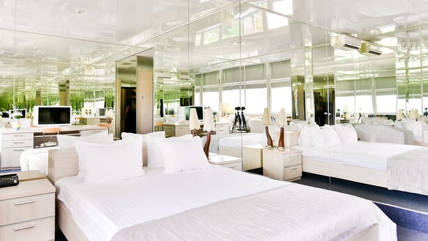 Une chambre d’hôtel moderne équipée d’un grand lit, de tables de chevet, d’un bureau et d’une télévision.