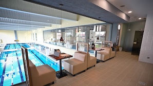 Un espace piscine intérieure moderne, doté de sièges et d’une horloge numérique.