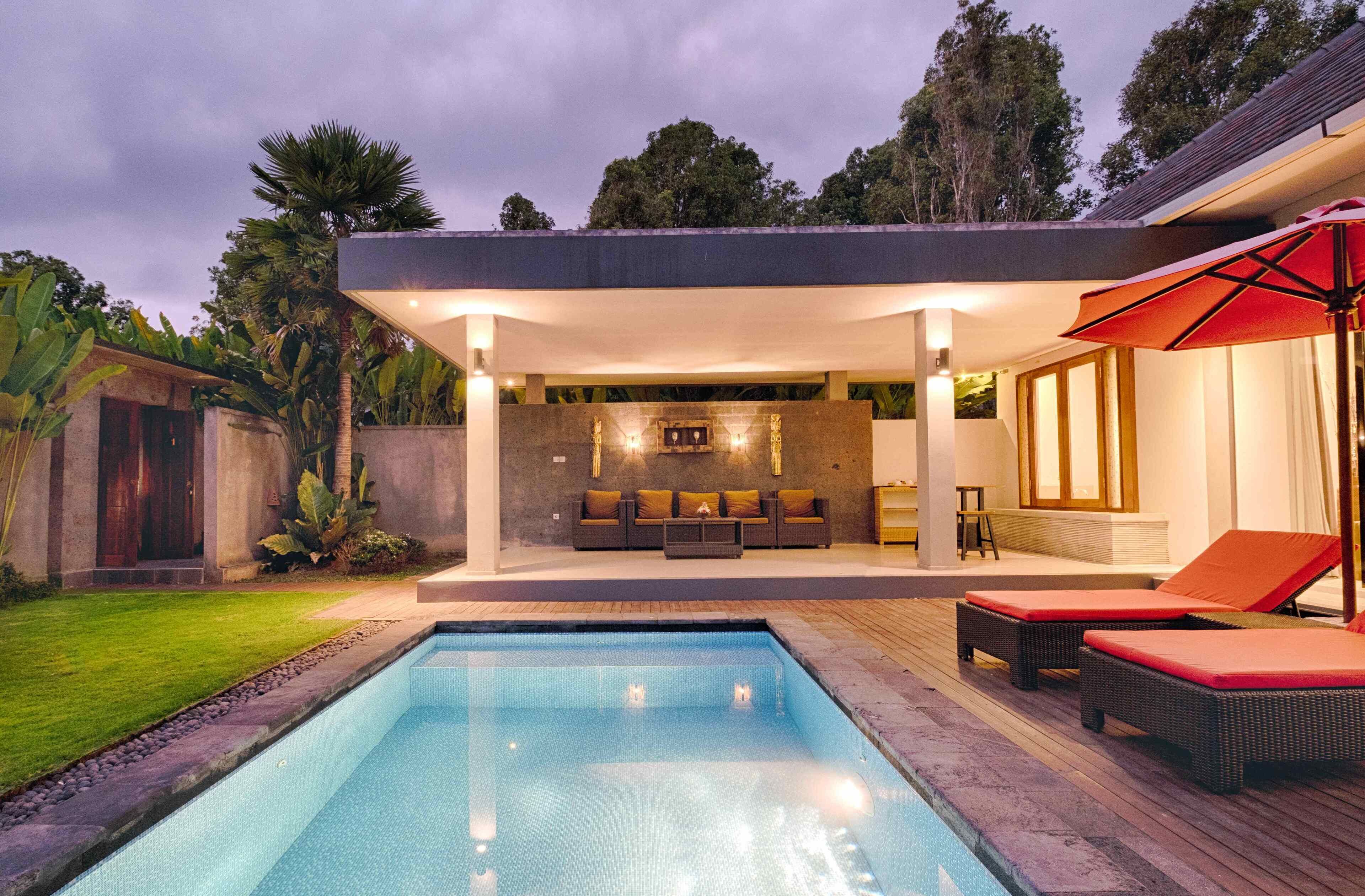 A modern outdoor pool area with a built-in seating area and a covered patio.