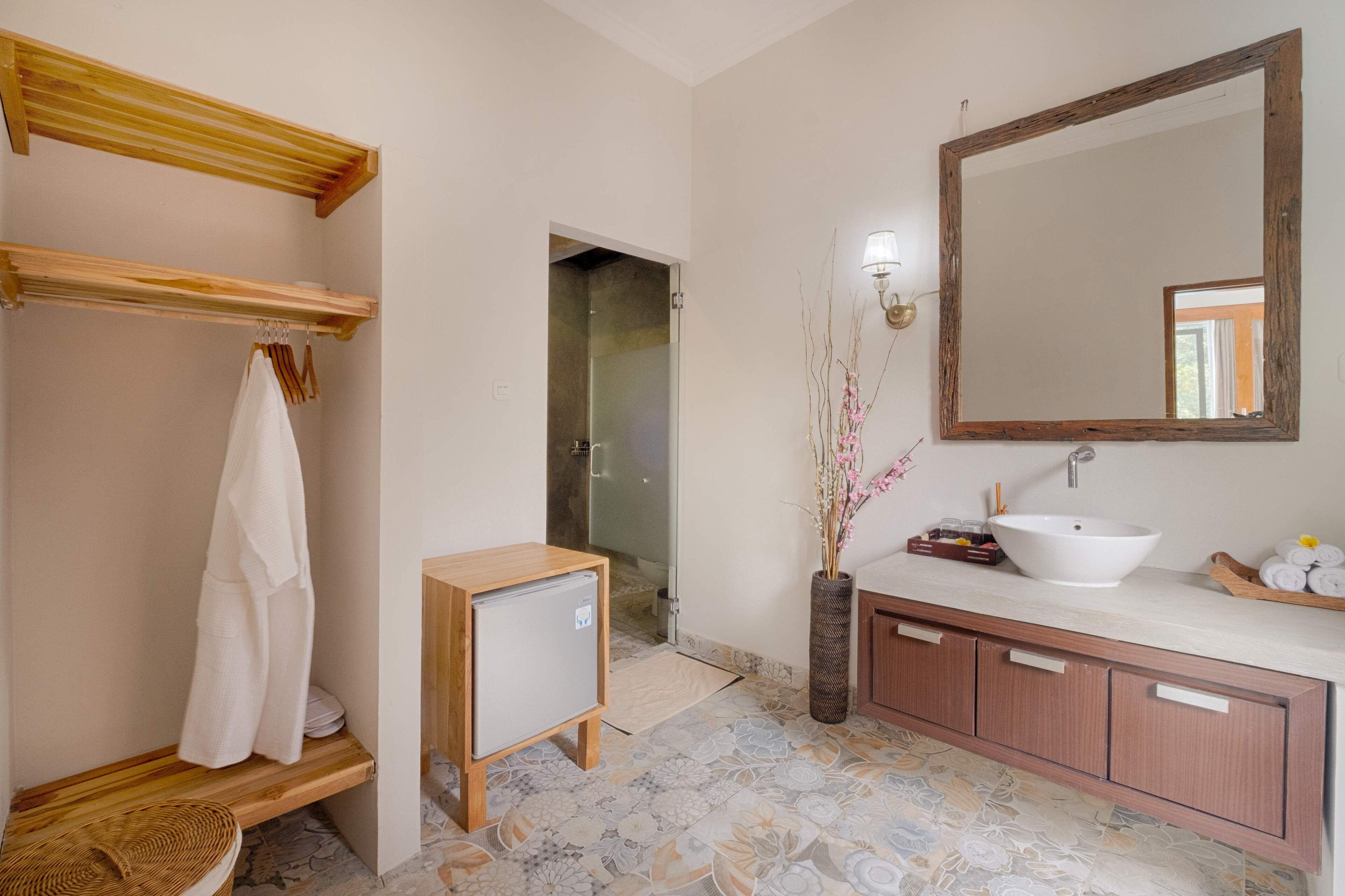 A bathroom with a wooden vanity, a large mirror, a sink, and a shower area.