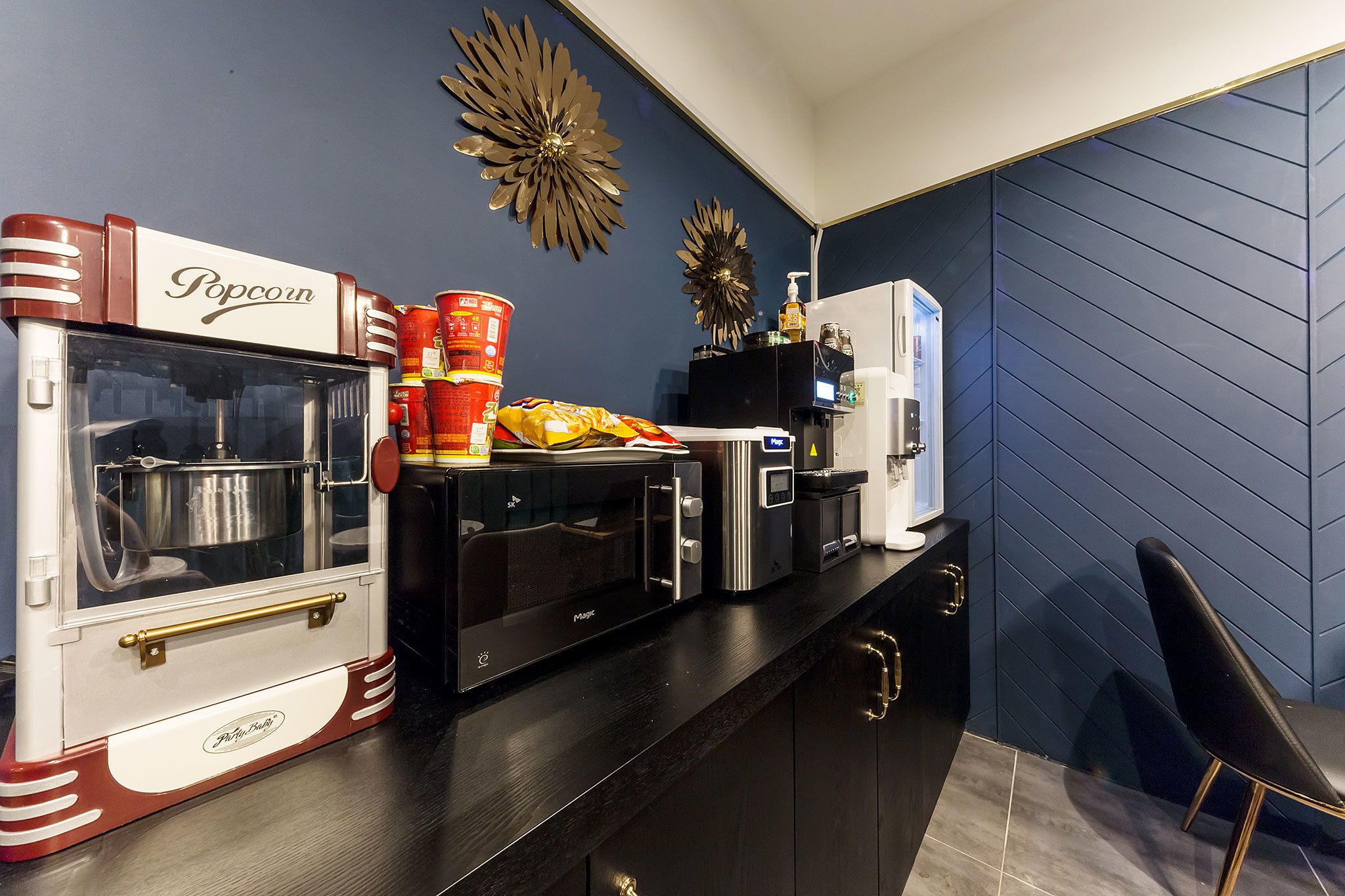 A kitchen with a popcorn machine, microwave, toaster, and coffee maker on the counter.