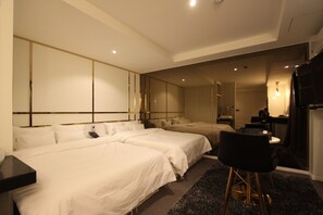 A hotel room with two beds, a desk, a chair, and a mirror.