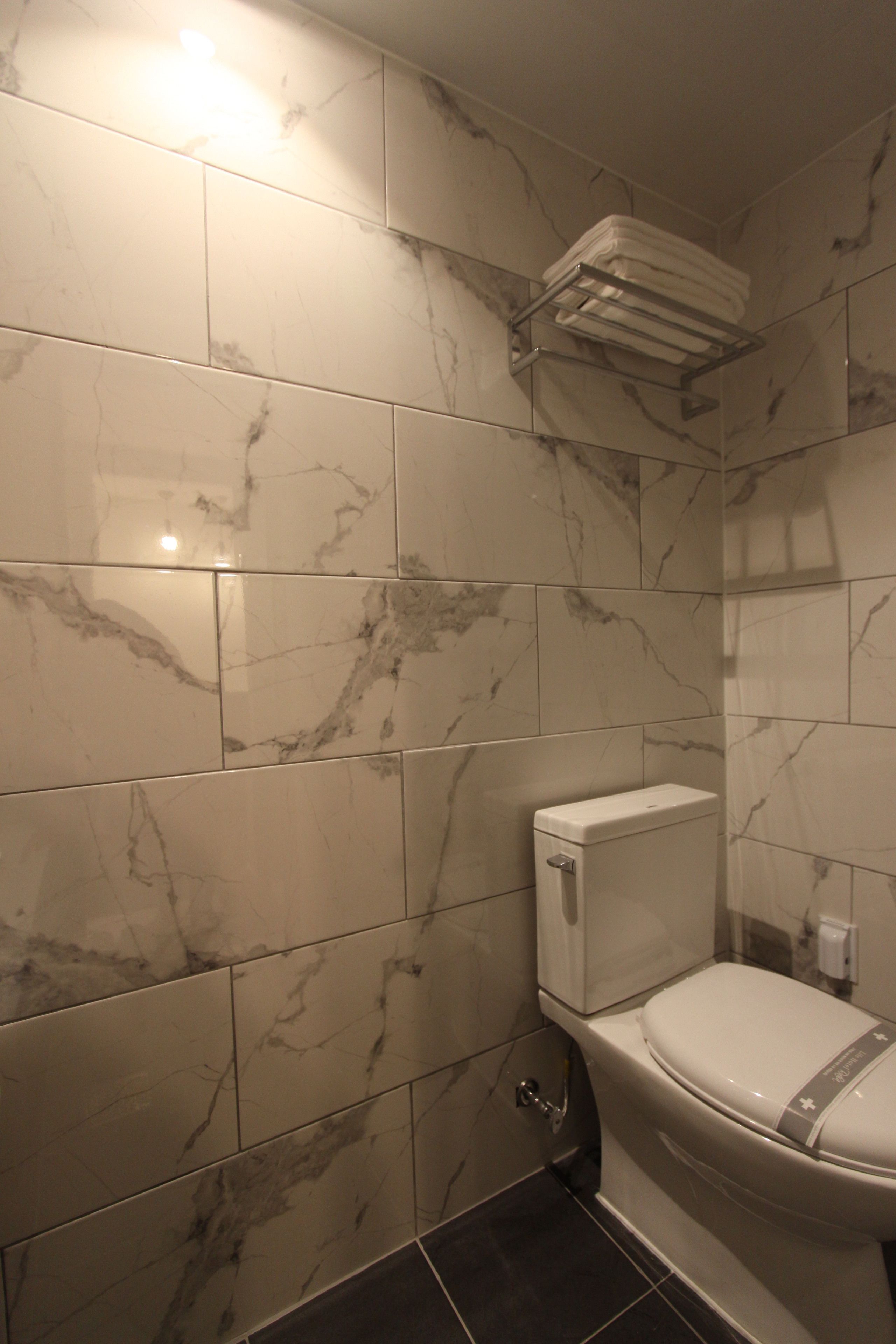 A bathroom with marble tiles, a toilet, and a towel rack.