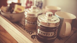 Two containers labeled 'COFFEE' and 'SUGAR' on a wooden tray.