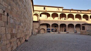 A courtyard with a stone building featuring multiple arches and a gravel ground. - Contessa Ava Dei Lambardi - Hostel (Monteriggioni)