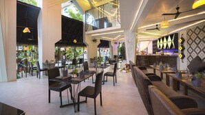A spacious indoor dining area with high ceilings, modern lighting, and a bar area in the background. - Natural House (Siem Reap)