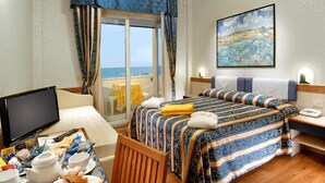 Habitación de hotel con cama, escritorio con computadora, televisor y mesa de desayuno.