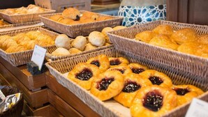 Una vitrina de panadería con diversos productos horneados, incluyendo croissants, muffins y pasteles con mermelada.