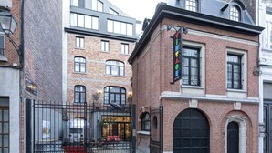 Un bâtiment en briques avec un portail noir, une table rouge et une enseigne indiquant qu’il s’agit d’un hôtel.