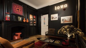 Un salon moderne avec une cheminée, un canapé, une table basse et un mur orné d’un panneau indiquant le mot « AMOUR ».