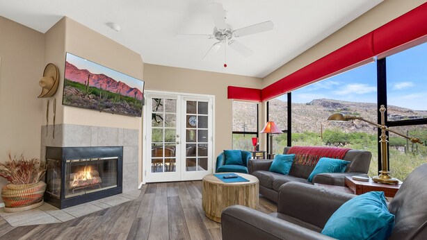 A living room with a fireplace, leather sofa, and a large window with a view of the desert.
