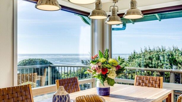 A dining table with chairs, a vase of flowers, and a plate of sliced bread.