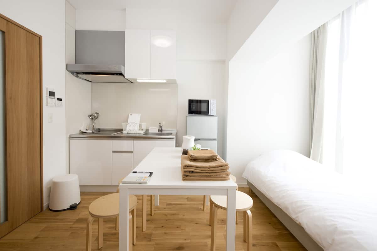 Een compacte, moderne kamer met kitchenette, eethoek en bed.