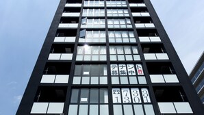 A modern building with multiple floors, large windows, and a visible entrance with a ramp. - OH Inn -Fukuoka Stay- (Fukuoka)