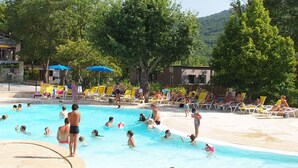Una piscina al aire libre, sombrillas, sillones reclinables de piscina