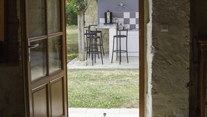 An open door leading to a kitchen with a stone wall and a view of a garden. - La Métairie du Clos Saint Louis (Montreal)