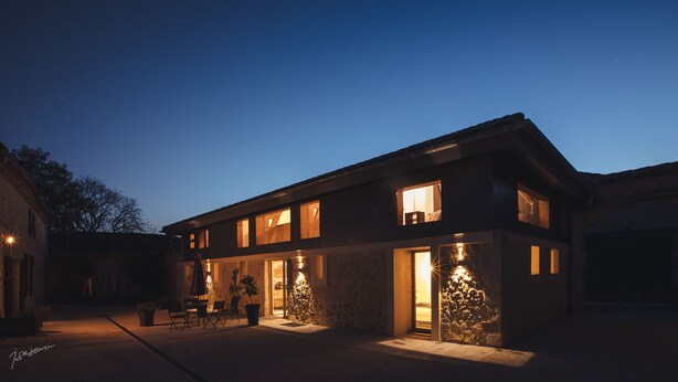 A modern two-story house with a stone facade, large windows, and a well-lit entrance. - La Métairie du Clos Saint Louis (Montreal)