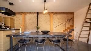 A modern dining area with a central table, four wire mesh chairs, a black bowl, and a vase with flowers. - La Métairie du Clos Saint Louis (Montreal)