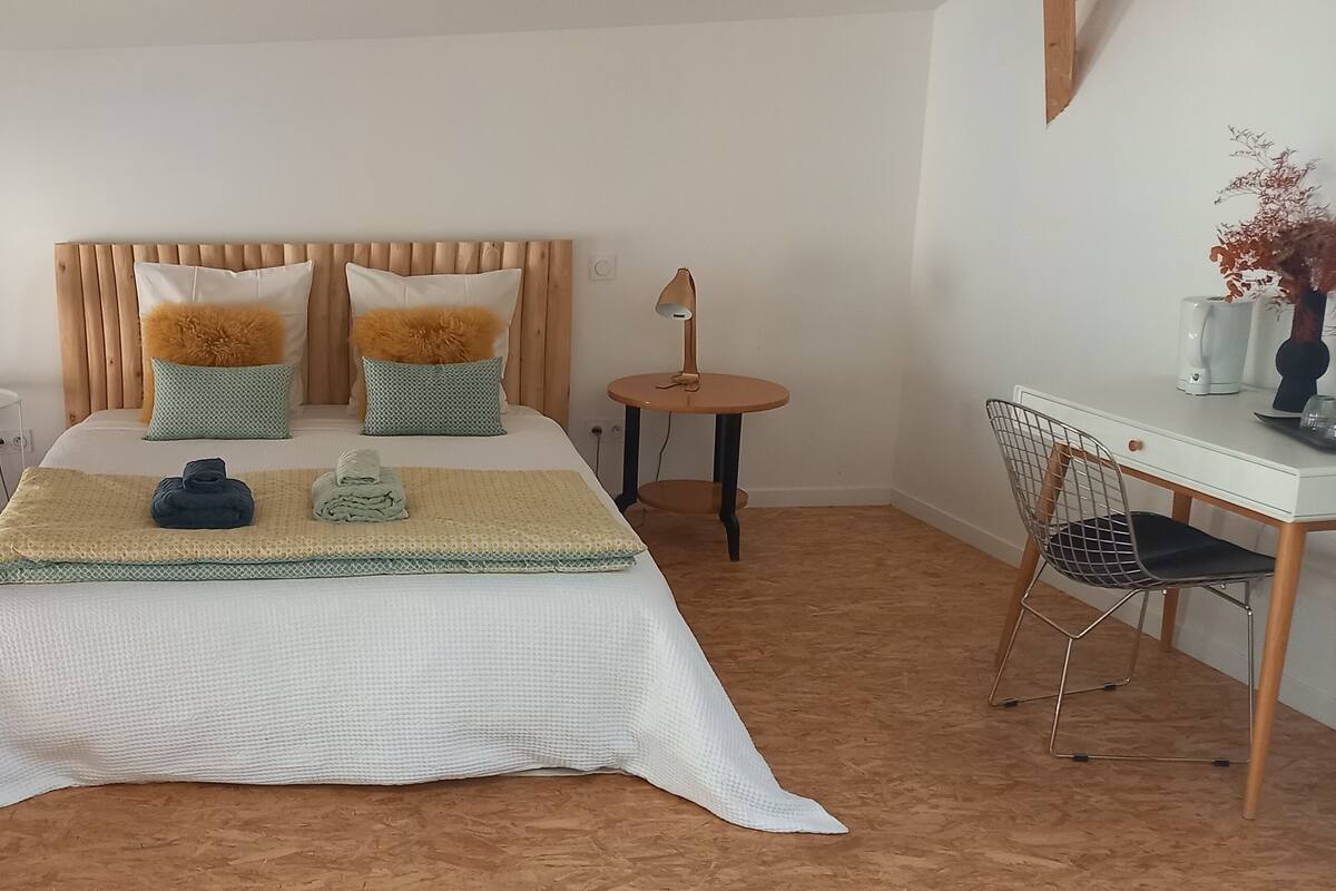 A bedroom with a large bed, two bedside tables, a small desk, and a chair.