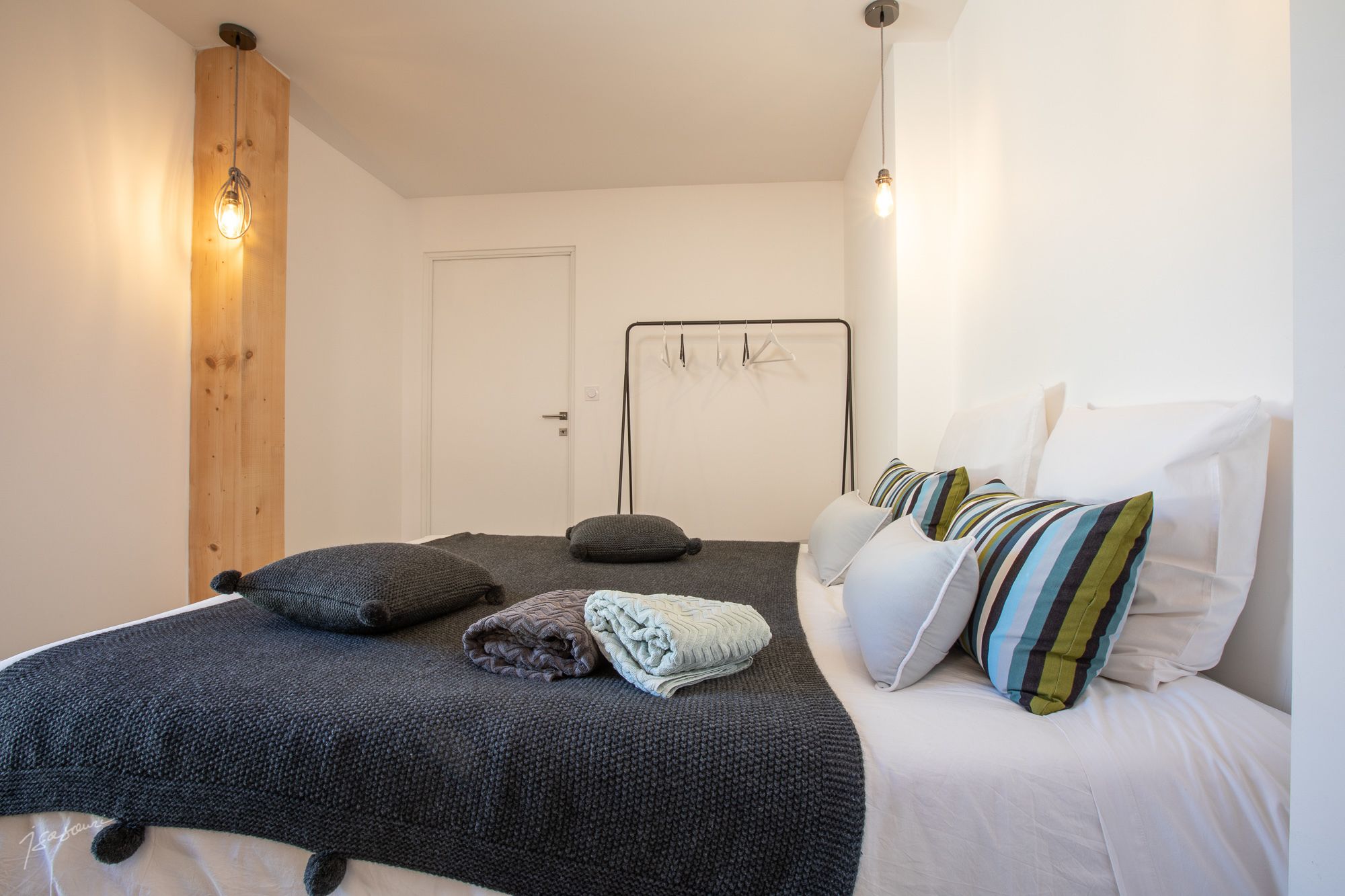 A bedroom with a bed, pillows, a wooden accent wall, and a metal bed frame.