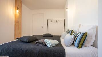 A bedroom with a bed, pillows, a wooden accent wall, and a metal bed frame.