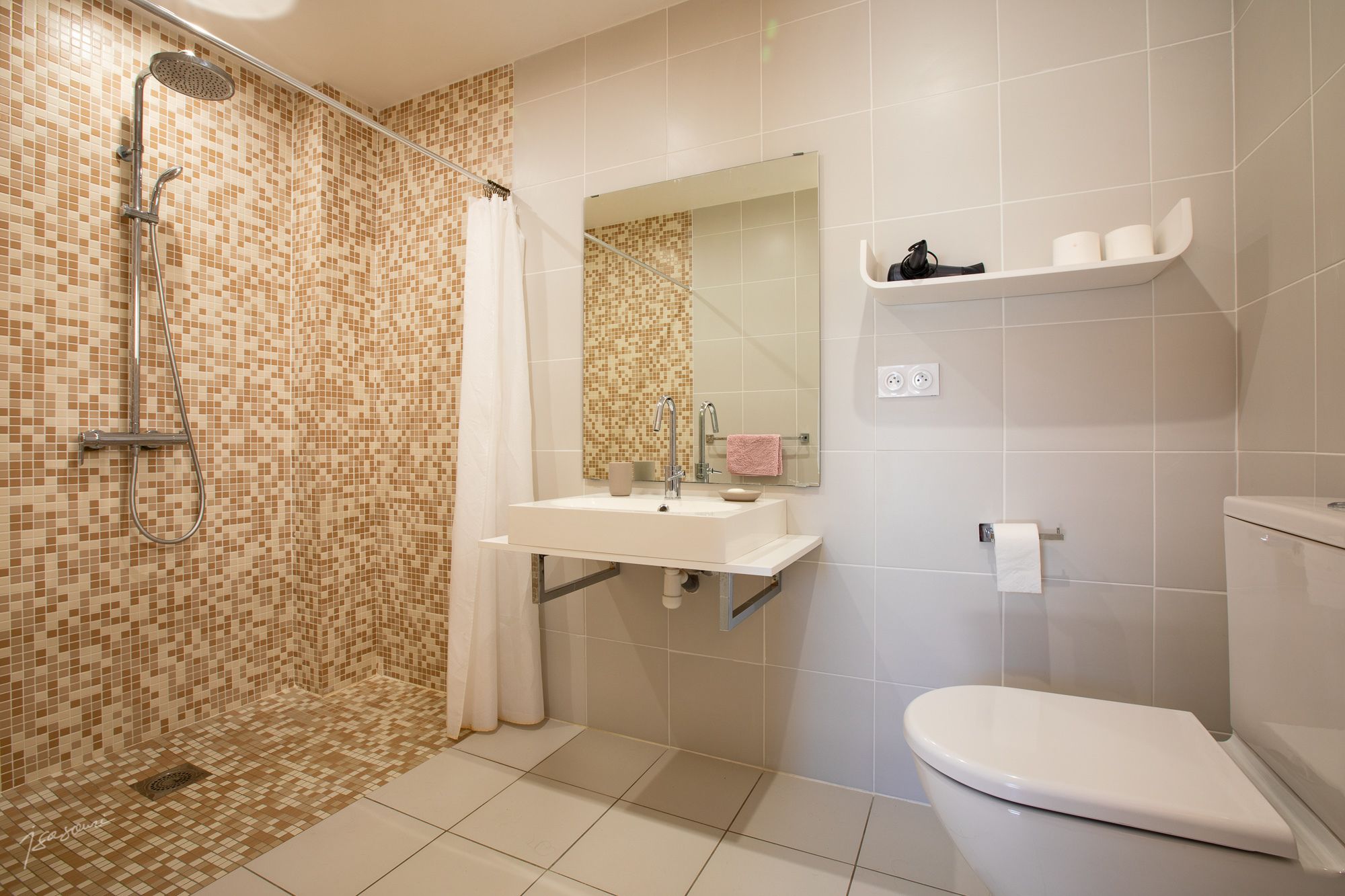 Ein Badezimmer mit Dusche, Waschbecken, Spiegel, Toilette und Fliesenwänden.