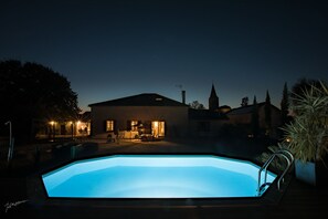 Een buitenzwembad, parasols bij het zwembad en ligstoelen